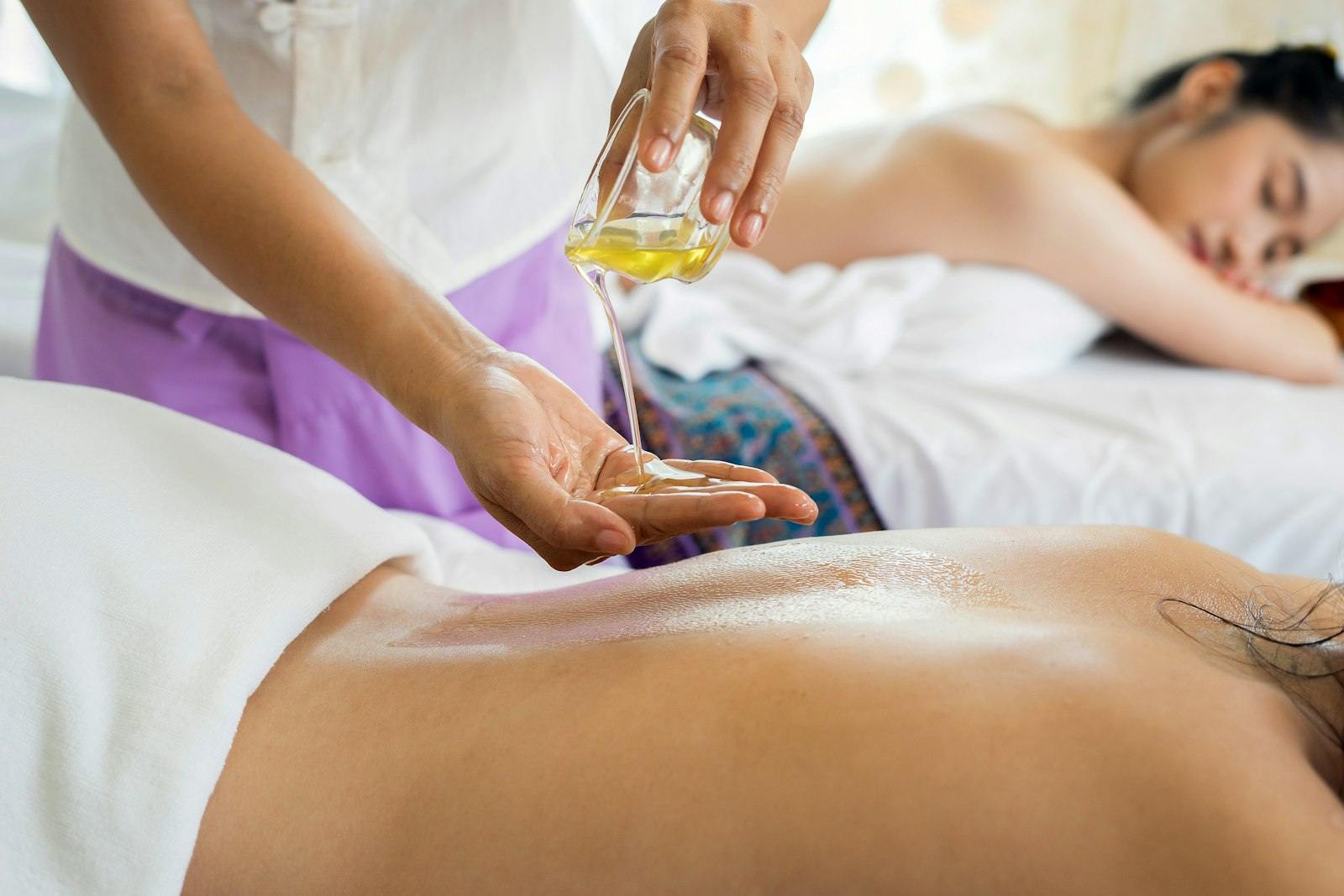 A Thai therapist warming aromatic oil in her hands before a treatment