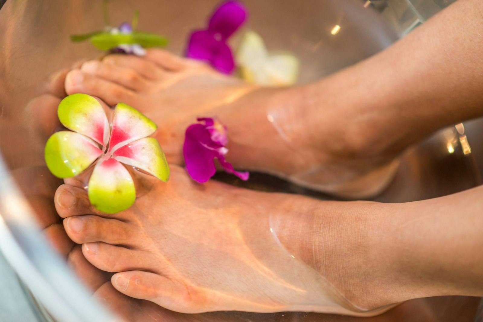Feet resting in a warm herbal foot soak before a foot reflexology treatment